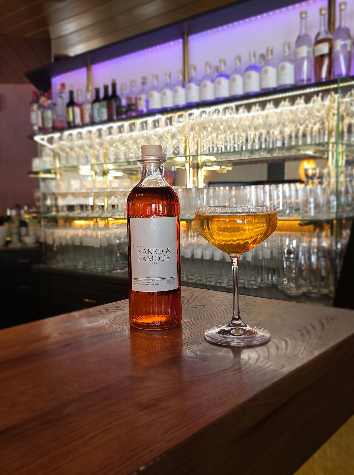 Naked & Famous Prebatch Erasmus Collection – Flasche und Coupe-Glas an der Bar